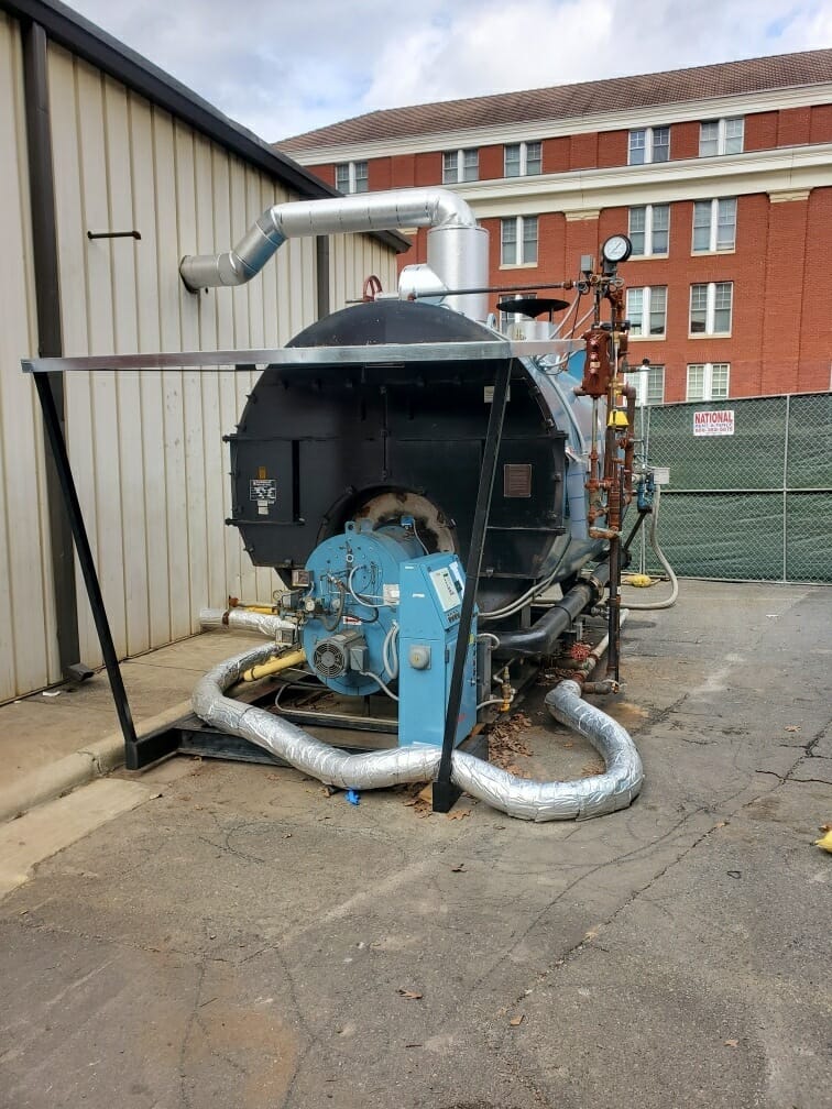 Steam boiler and burner set up outside a building, front view