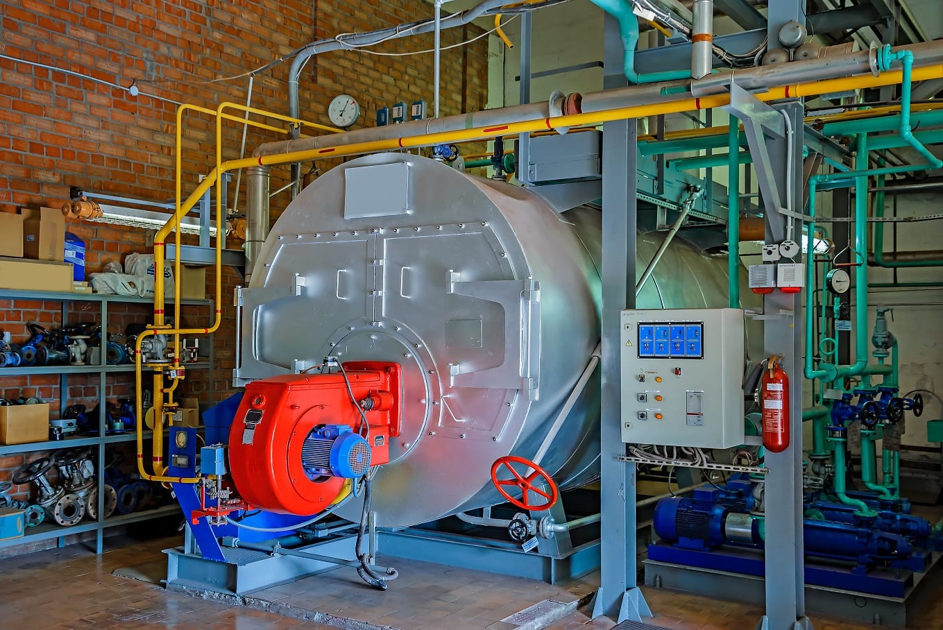 Boiler with a red burner, control panel, and pumps in a boiler room